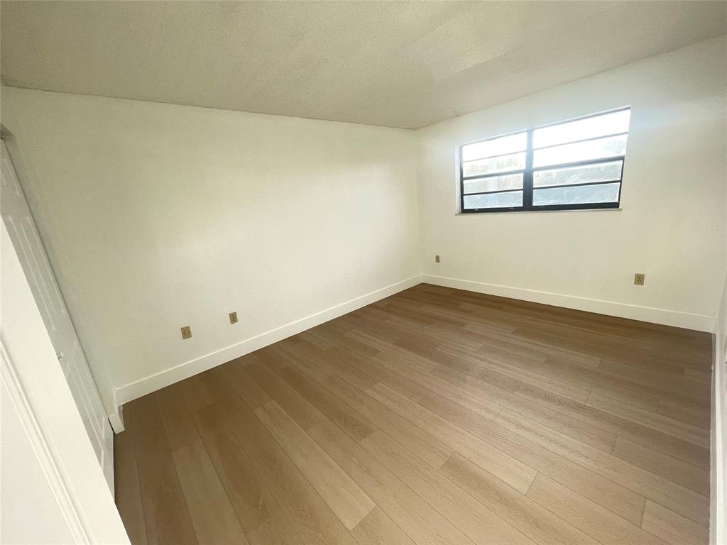 1470 West 41st Street, Unit 201 Hialeah, FL 33012 - Photo 16 of 26 an empty room with wooden floor and windows