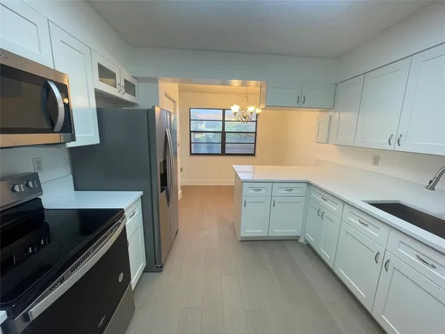 a view of a kitchen with a sink a refrigerator and a chandelier