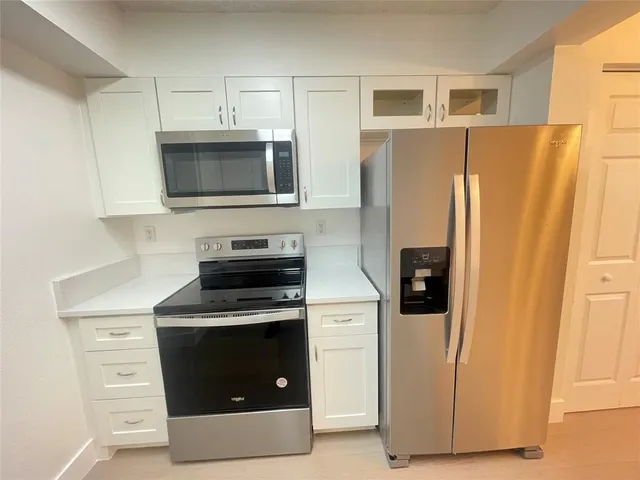 a kitchen with granite countertop white cabinets and white appliances