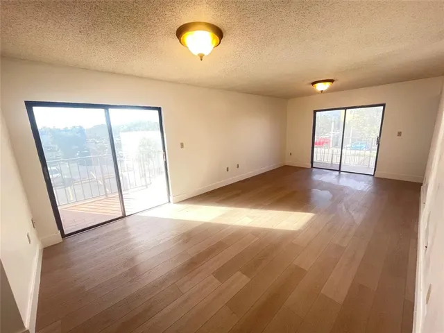 a view of an empty room with wooden floor and windows