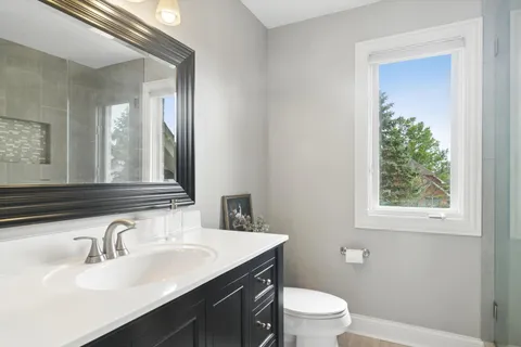 a bathroom with a granite countertop sink toilet a large mirror and shower