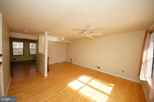 a view of an empty room with wooden floor and a ceiling fan