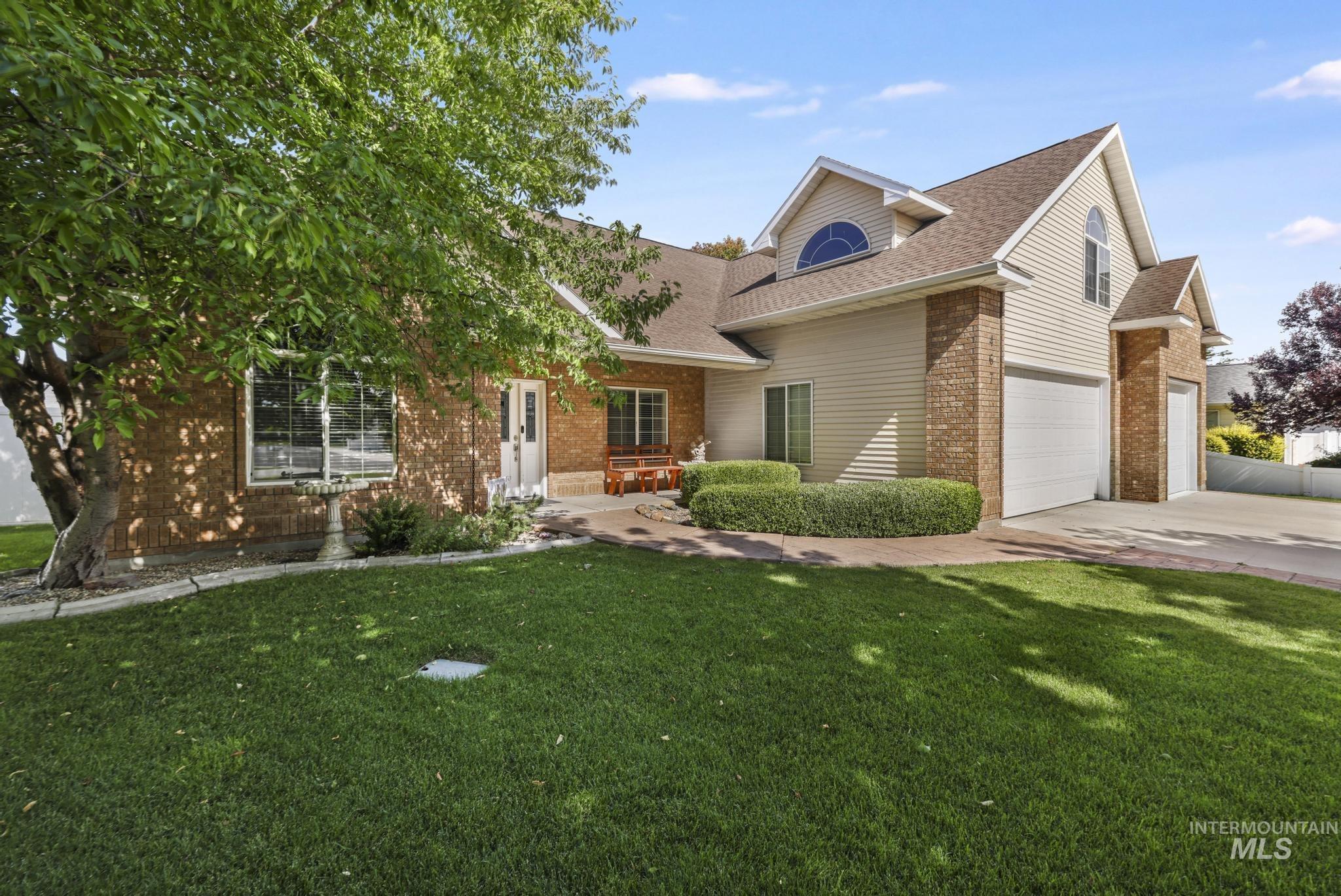 467 Wildrose Loop Twin Falls, ID 83301 - Photo 4 of 46 Brick and siding exterior featuring a multi-car garage, pitched roof, arched window dormer, and well-maintained front lawn