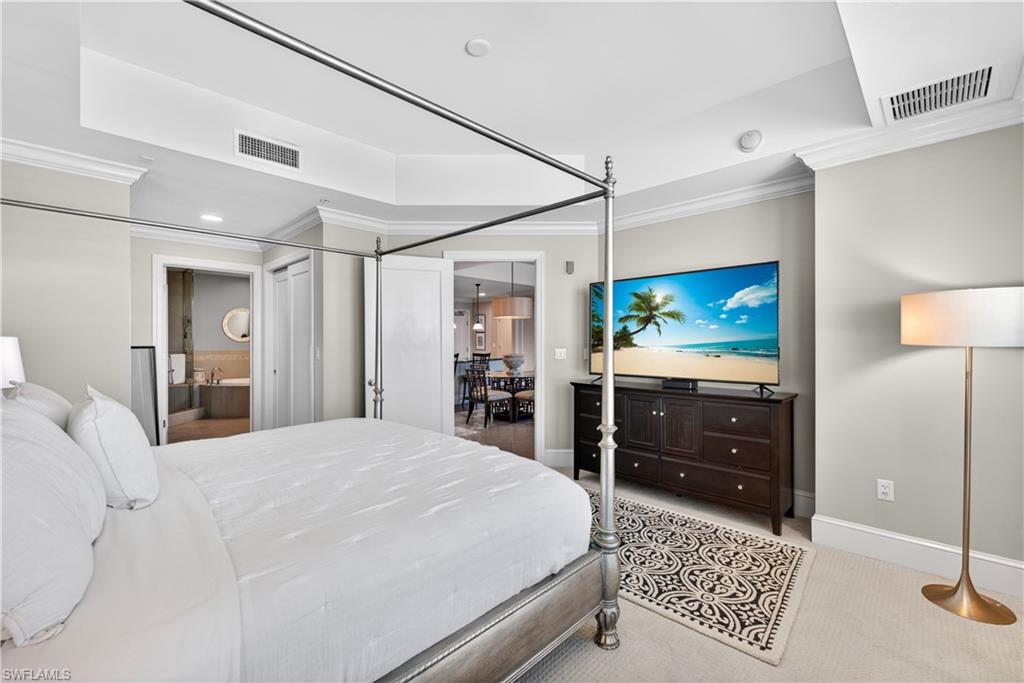9115 Strada Place, Unit 5504 Naples, FL 34108 - Photo 9 of 22 a large bedroom with a bed and a flat tv screen on dresser