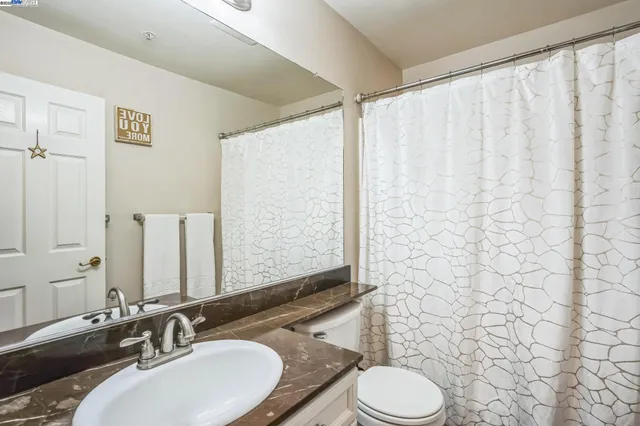 a bathroom with a granite countertop sink toilet and a mirror
