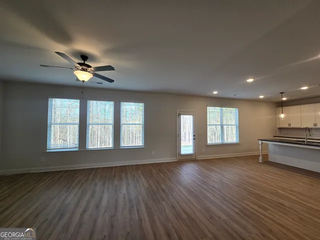 a view of an empty room with a window and wooden floor