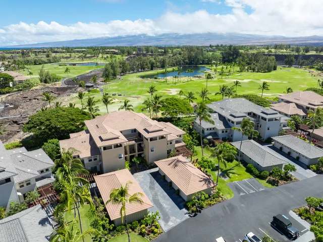 an aerial view of a houses with garden space and ocean view