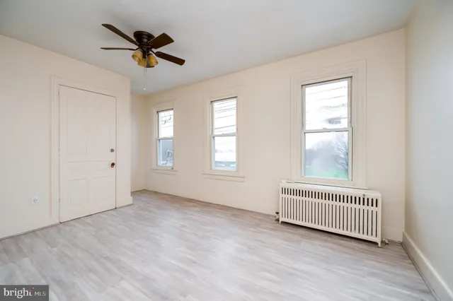 a view of empty room with wooden floor and fan