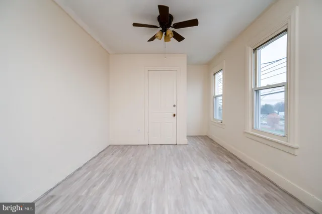 an empty room with windows and fan