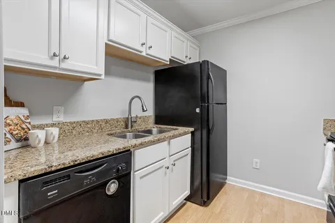 a kitchen with granite countertop white cabinets and a sink