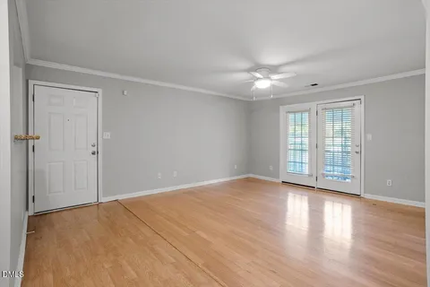 a view of an empty room with window and wooden floor