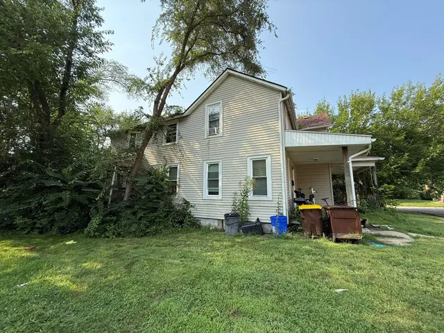 a backyard of a house with table and chairs plants and large tree