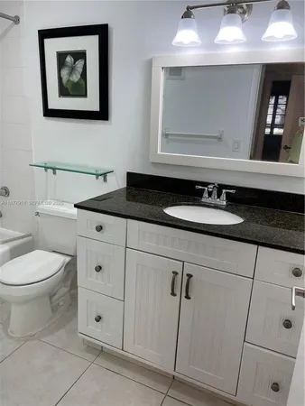 a bathroom with a granite countertop toilet sink and mirror
