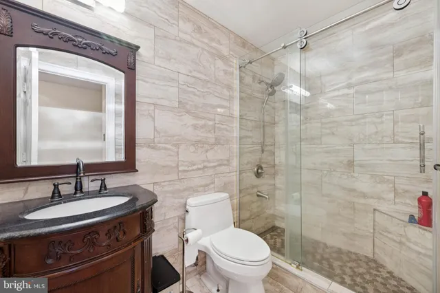 a bathroom with a granite countertop sink toilet a mirror and shower