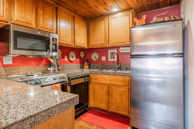 a kitchen with stainless steel appliances granite countertop a refrigerator a stove and a wooden floor