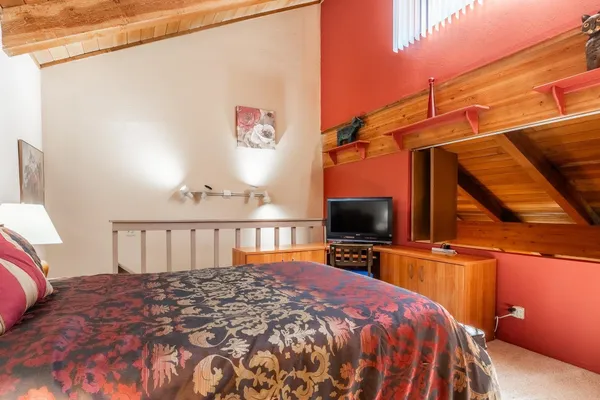 a bedroom with a bed and a flat tv screen on the dresser