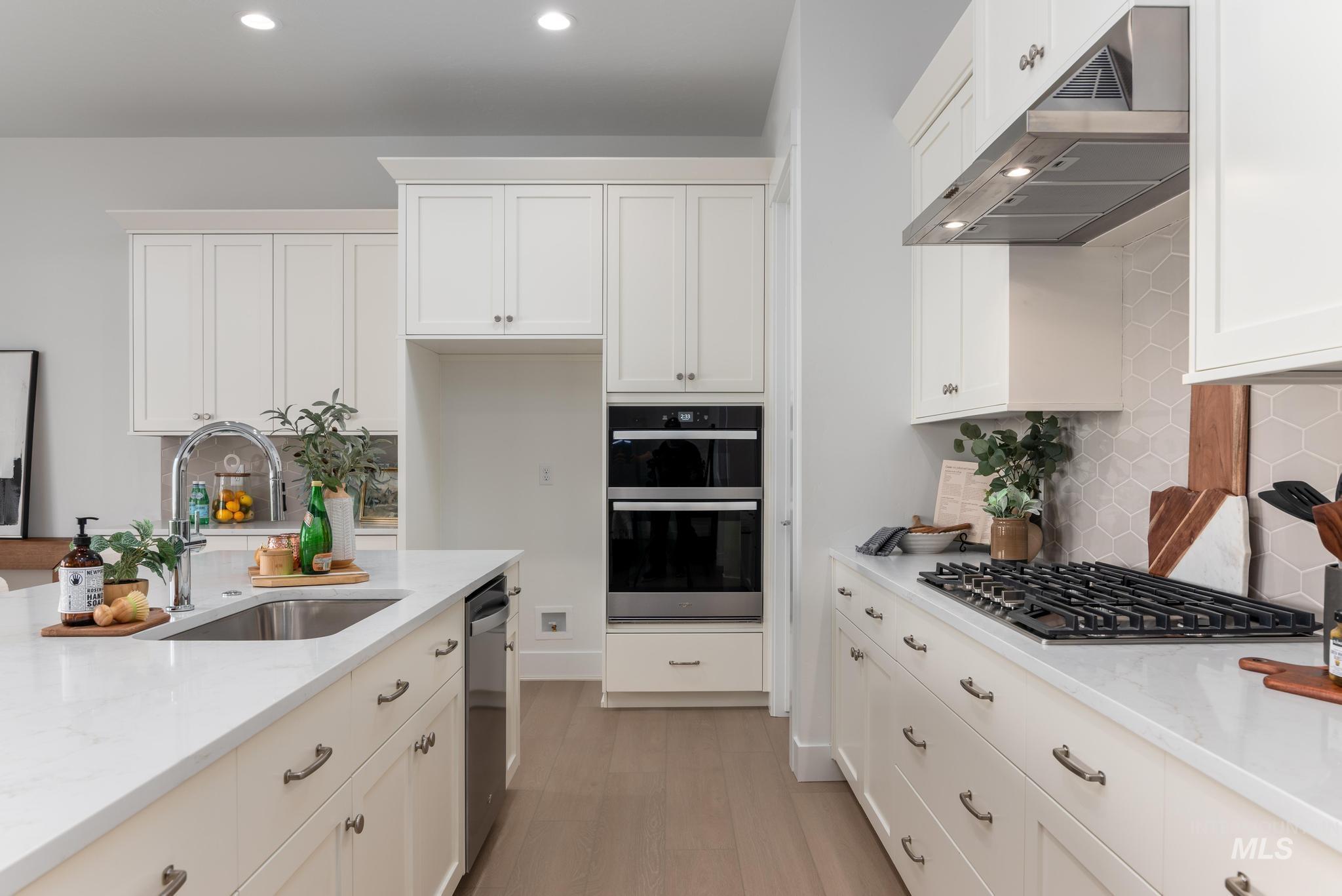 8501 South Country Wind Avenue Meridian, ID 83642 - Photo 11 of 39 Bright kitchen featuring white cabinetry, light countertops, wood-finish flooring, a built-in oven and microwave, and a gas cooktop with a stainless steel range hood