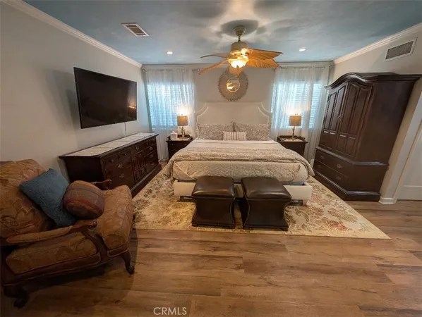 a spacious bedroom with a bed a mirror on dresser and a flat screen tv
