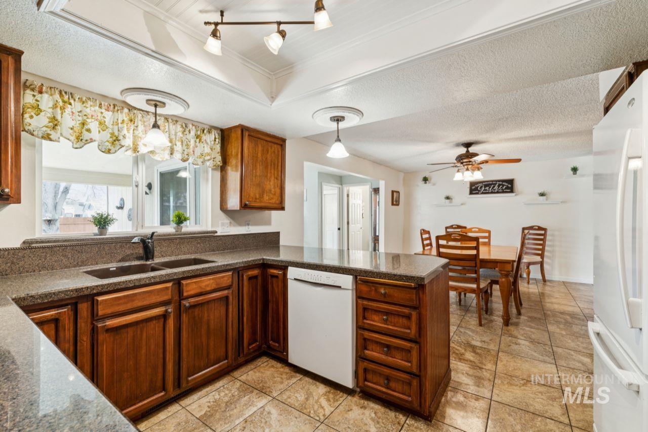 4093 North Marylebone Way Boise, ID 83713 - Photo 12 of 48 Kitchen featuring a textured ceiling, white appliances, a peninsula, decorative light fixtures, and wood finish cabinets