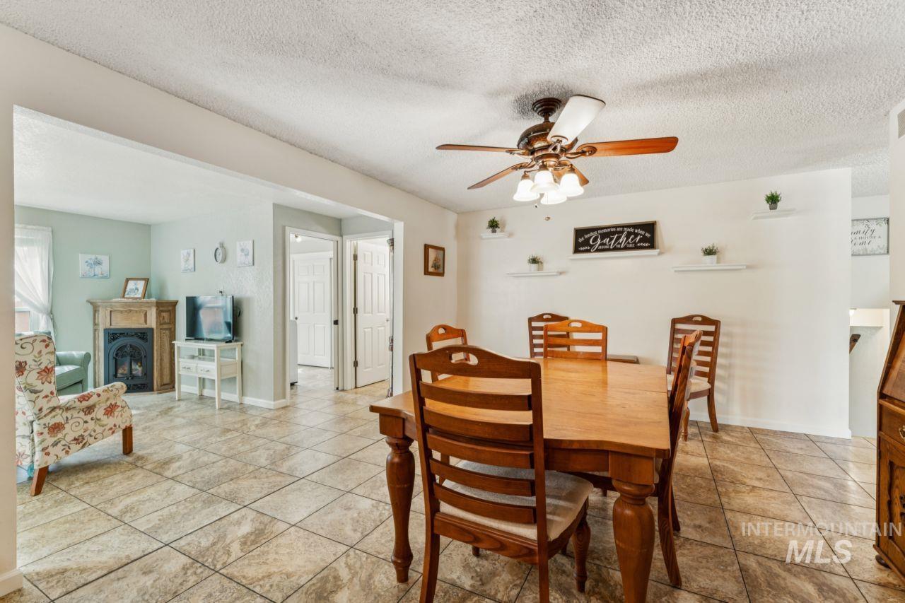 4093 North Marylebone Way Boise, ID 83713 - Photo 13 of 48 Dining space featuring a ceiling fan, a textured ceiling, and a fireplace