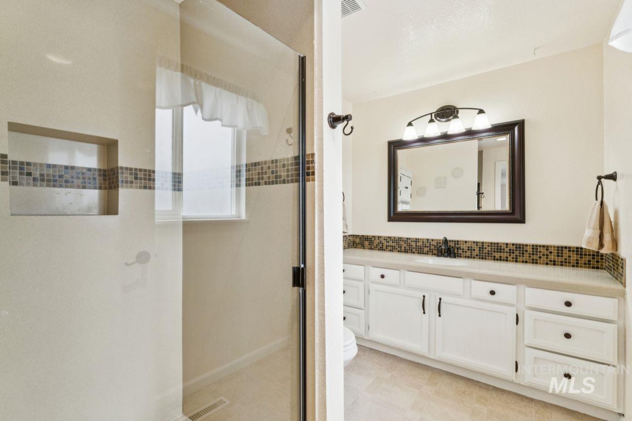 4093 North Marylebone Way Boise, ID 83713 - Photo 21 of 48 Full bathroom featuring vanity, a shower stall, decorative backsplash, and light floors
