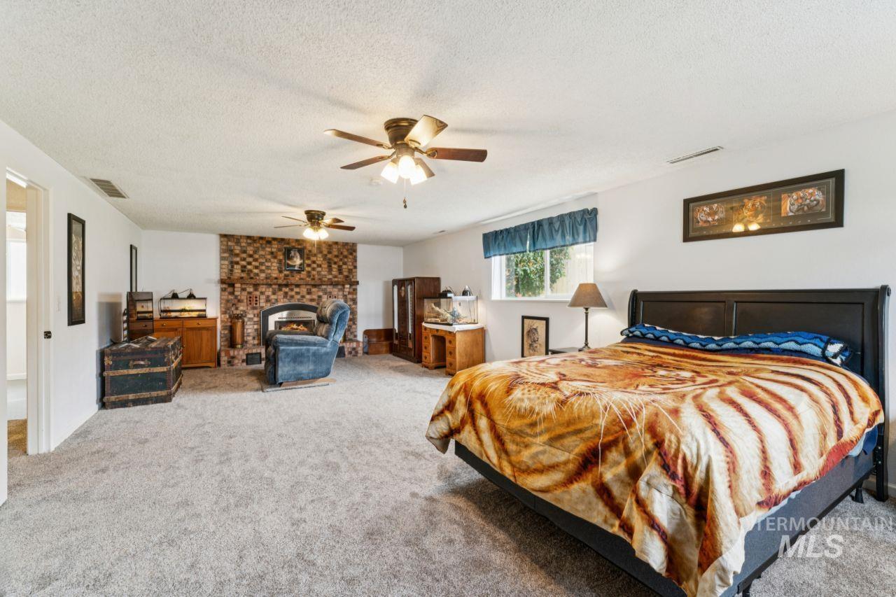 4093 North Marylebone Way Boise, ID 83713 - Photo 29 of 48 Carpeted bedroom featuring a ceiling fan, a fireplace, and a textured ceiling