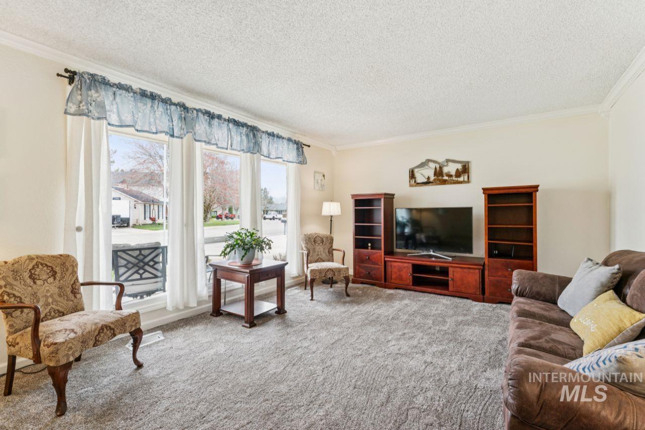 4093 North Marylebone Way Boise, ID 83713 - Photo 6 of 48 Living room featuring carpet flooring, crown molding, and a textured ceiling
