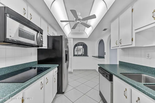 a view of an empty room and chandelier fan