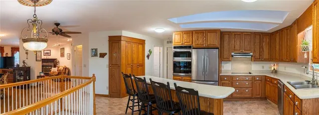a kitchen with stainless steel appliances granite countertop a refrigerator a sink dishwasher a stove and a dining table with wooden floor