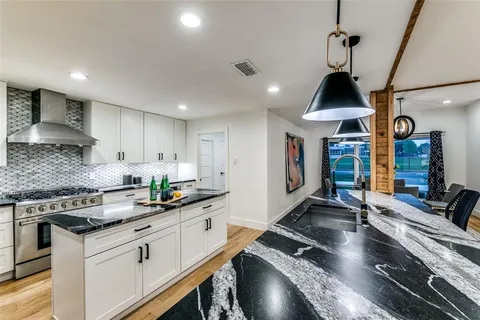 a kitchen with stainless steel appliances granite countertop a sink a stove and cabinets
