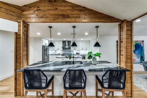 a kitchen with stainless steel appliances granite countertop a table chairs in it and wooden floor