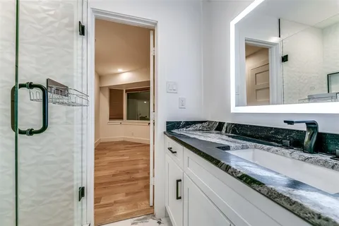 a bathroom with a granite countertop sink a mirror and shower