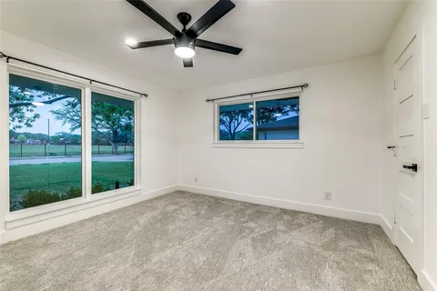 an empty room with windows and ceiling fan