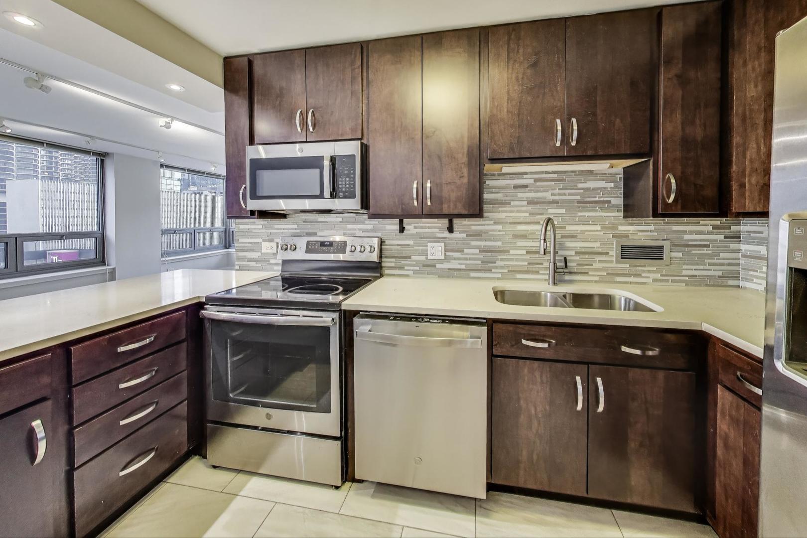 440 North Wabash Avenue, Unit 1605 Chicago, IL 60611 - Photo 19 of 53 a kitchen with stainless steel appliances granite countertop wooden cabinets and a stove top oven