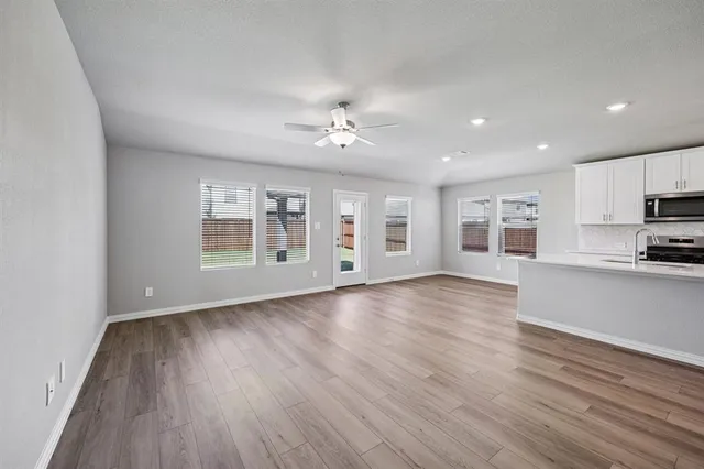 a view of an empty room with window and wooden floor