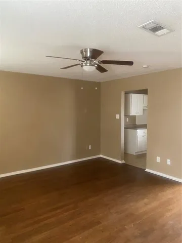 a view of an empty room with a ceiling fan and window