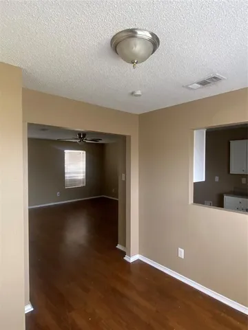 a view of an empty room with window and wooden floor