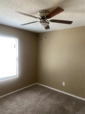 an empty room with a window and a fan