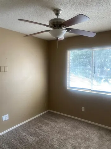 an empty room with a ceiling fan and window