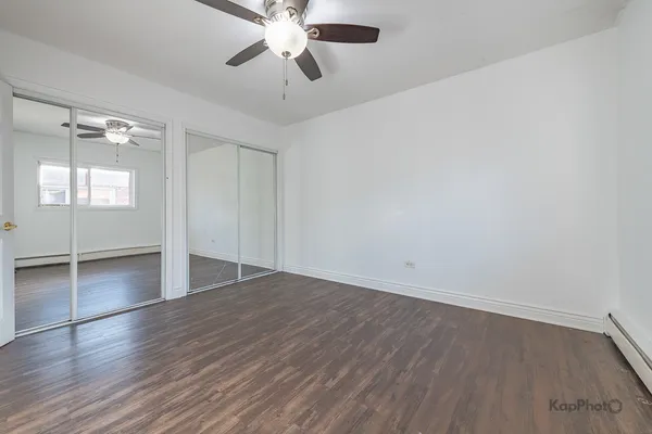 an empty room with wooden floor chandelier fan and windows