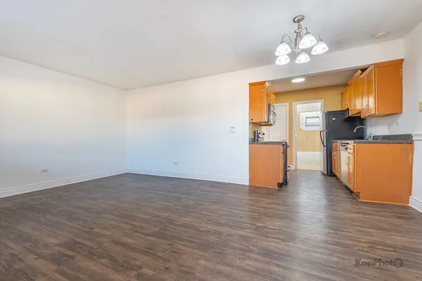 an empty room with wooden floor and chandelier