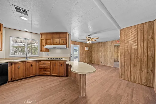 an empty room with wooden floor chandelier fan and windows