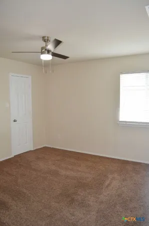 an empty room with a window and ceiling fan