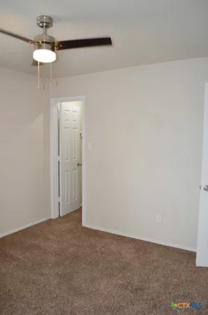 a view of an empty room and a chandelier fan