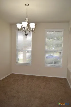 a view of a livingroom with a chandelier fan and windows