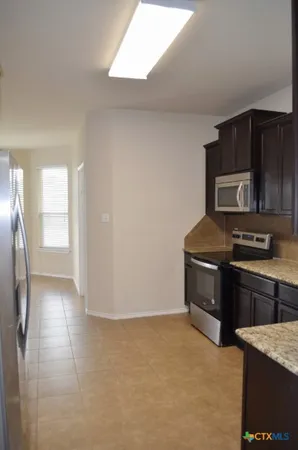 a kitchen with granite countertop a refrigerator stove and microwave
