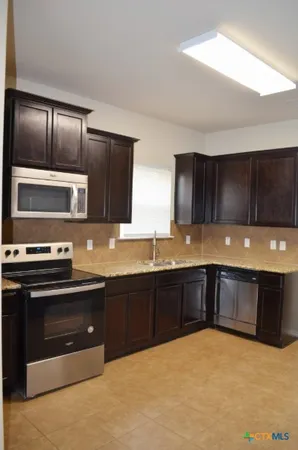 a kitchen with stainless steel appliances granite countertop a sink stove and microwave