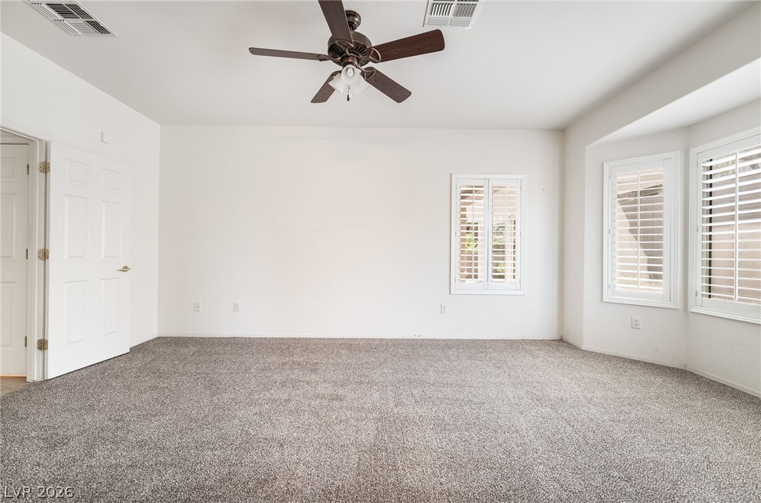3033 Hartsville Road Henderson, NV 89052 - Photo 27 of 41 A spacious, naturally illuminated room features plush carpeting, classic white plantation shutters, and a modern ceiling fan.