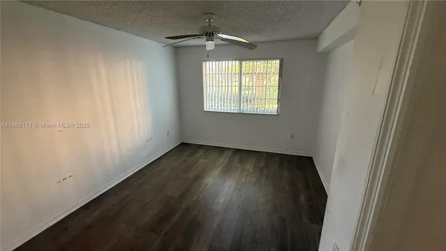 an empty room with wooden floor cabinet and windows
