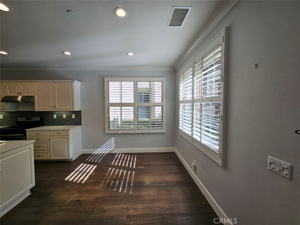 35 Courant Irvine, CA 92618 - Photo 9 of 37 a kitchen with granite countertop a stove and white cabinets with wooden floor